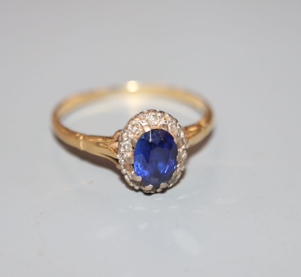 An 18ct, synthetic sapphire and diamond set oval cluster ring, size T, gross 3.2 grams.